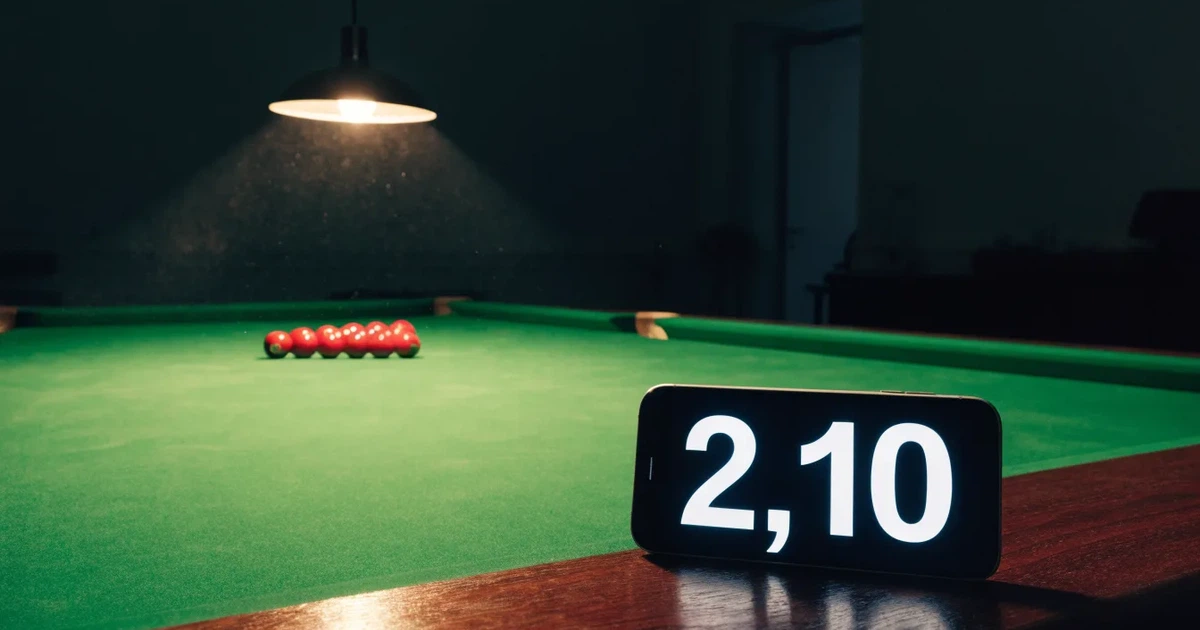 Ein Snookertisch mit grünem Tuch und aufgebauten roten Kugeln in einem abgedunkelten Raum unter einer hängenden Lampe.