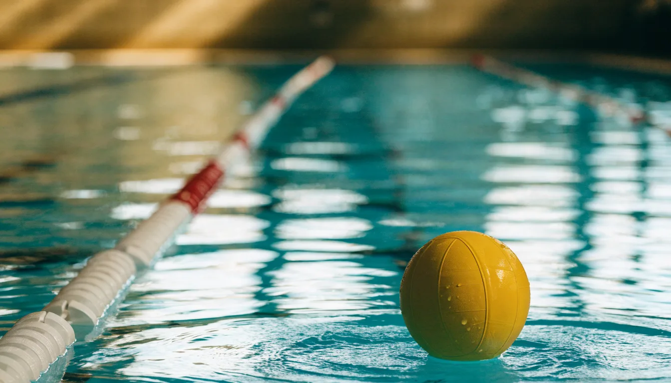 Ein gelber Wasserball treibt in Nahaufnahme auf der Wasseroberfläche neben einer Leine mit Bojen.